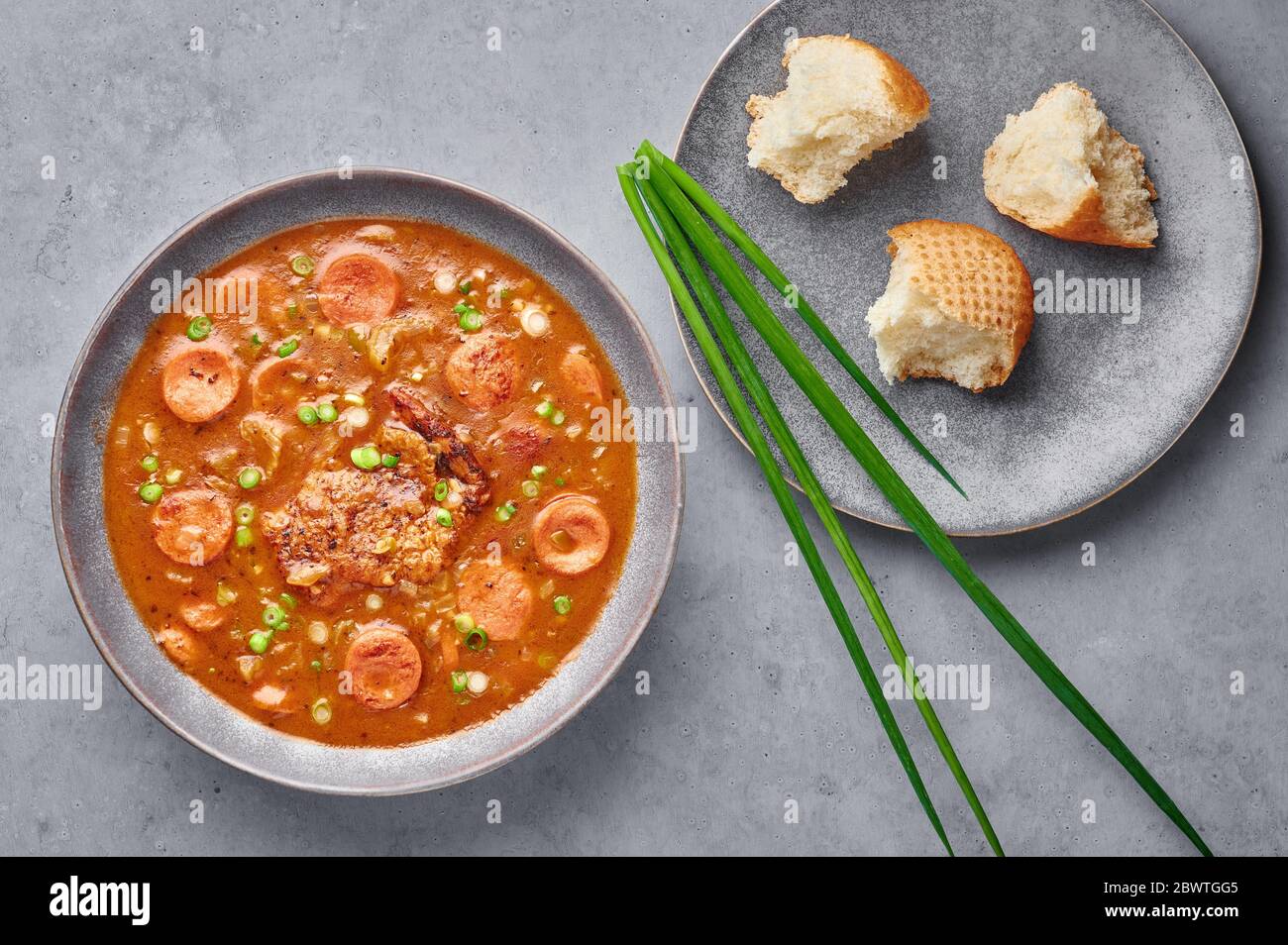 Chicken and Sausage Gumbo soup in gray bowl on concrete backdrop. Gumbo