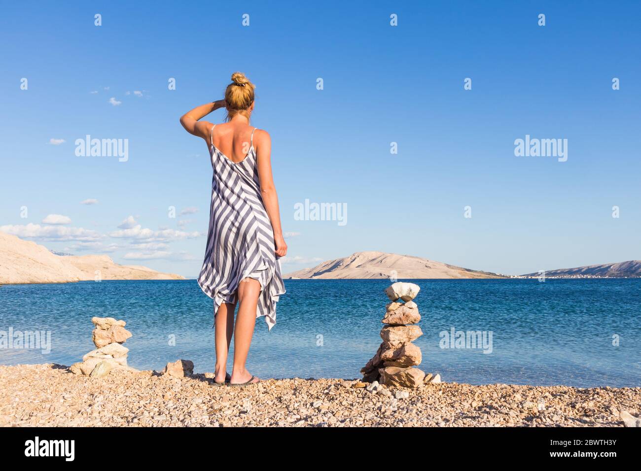 Happy carefree woman enjoying late afternoon walk on white pabbled beach on Pag island, Croatia Stock Photo