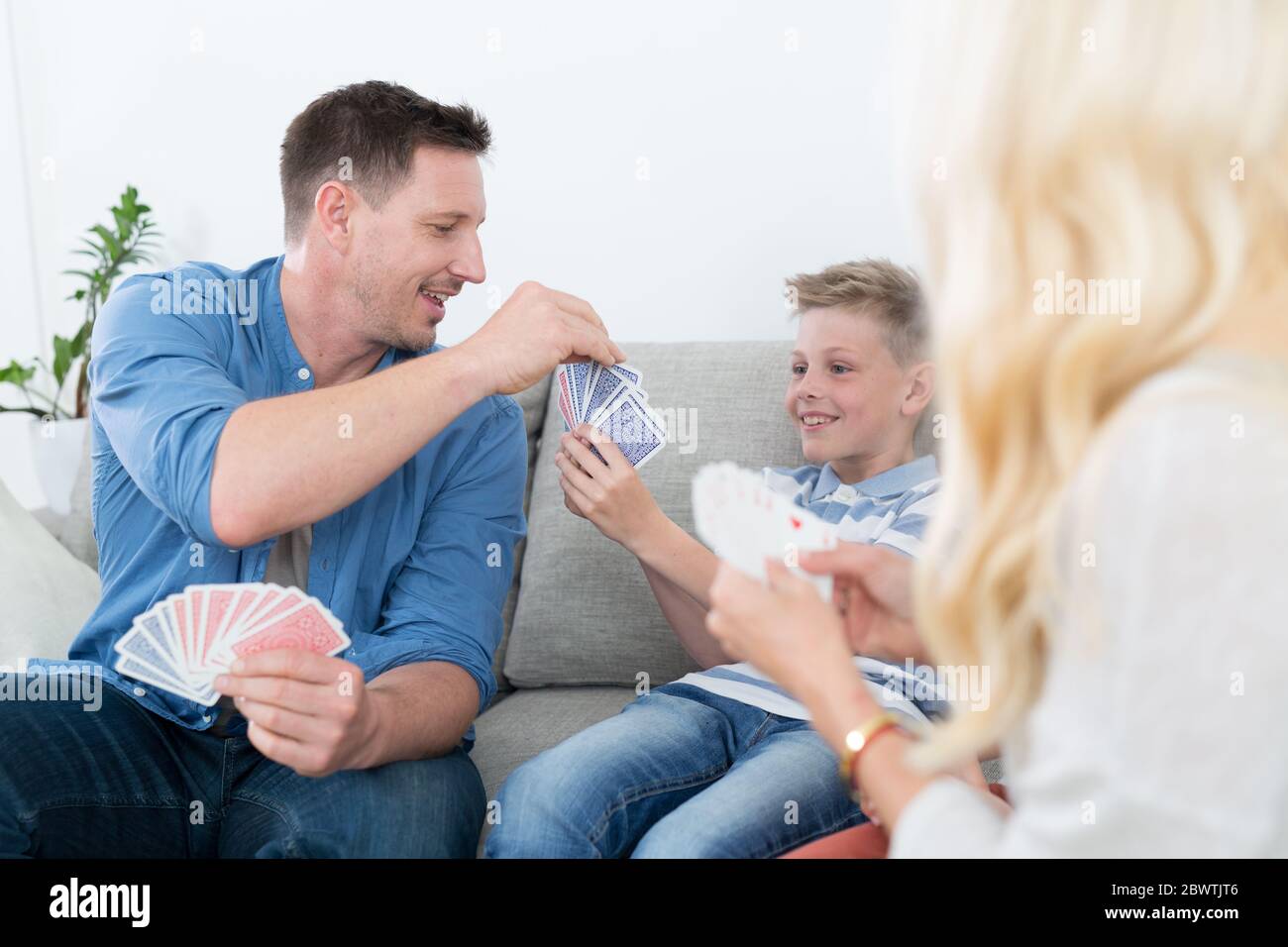 Happy young family playing card game at home Stock Photo - Alamy