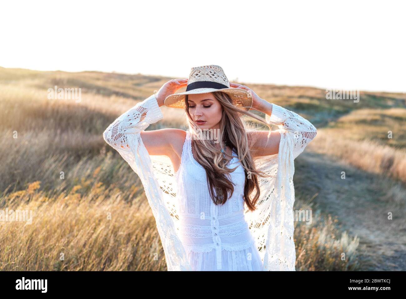 Beautiful woman wearing in white dress and straw hat enjoying nature ...