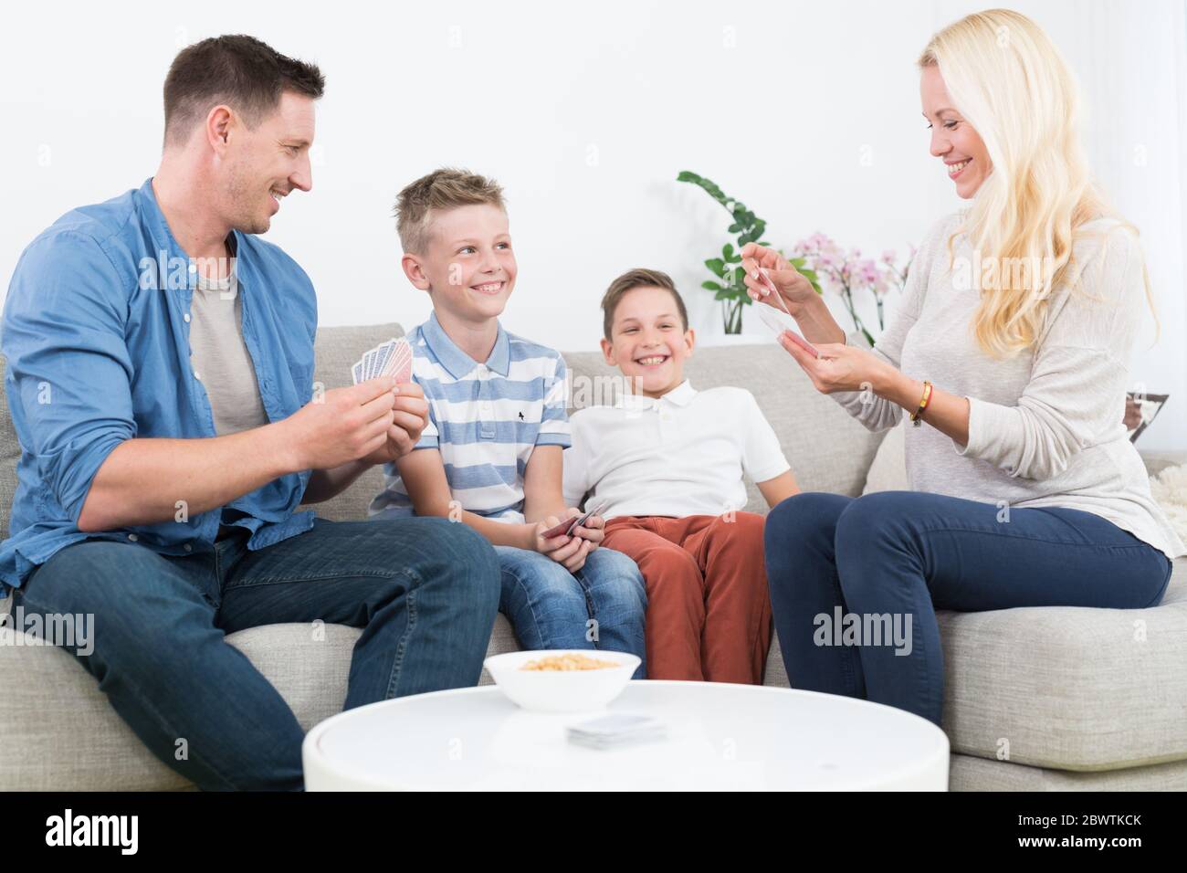 Happy young family playing card game at home. Stock Photo