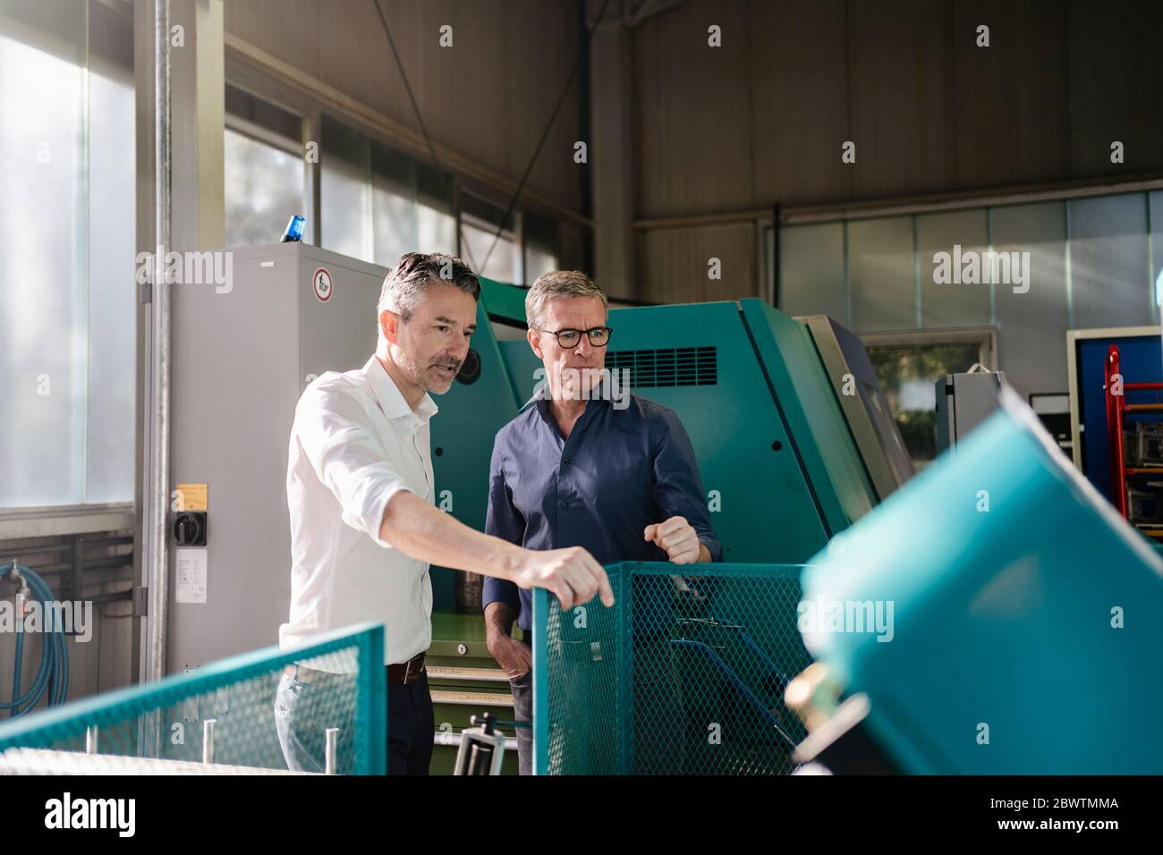 Businessmen in factory, having a meeting, discussing solutions Stock Photo