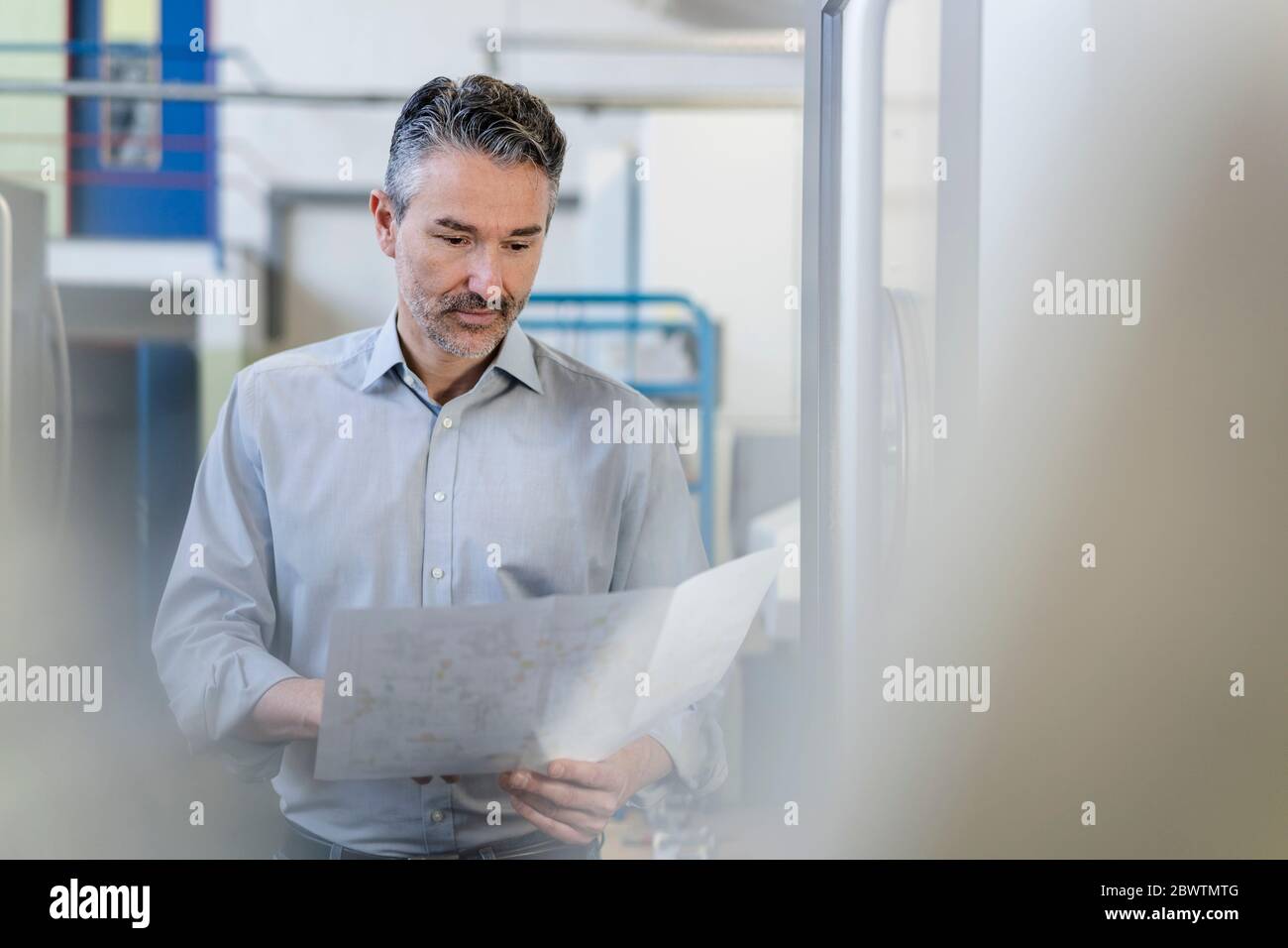 Competent businessman working in his company, looking at plan Stock Photo