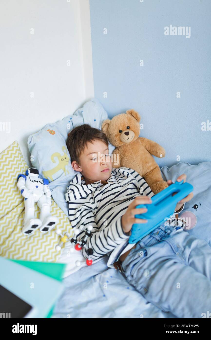 Boy lying in bed using digital tablet Stock Photo