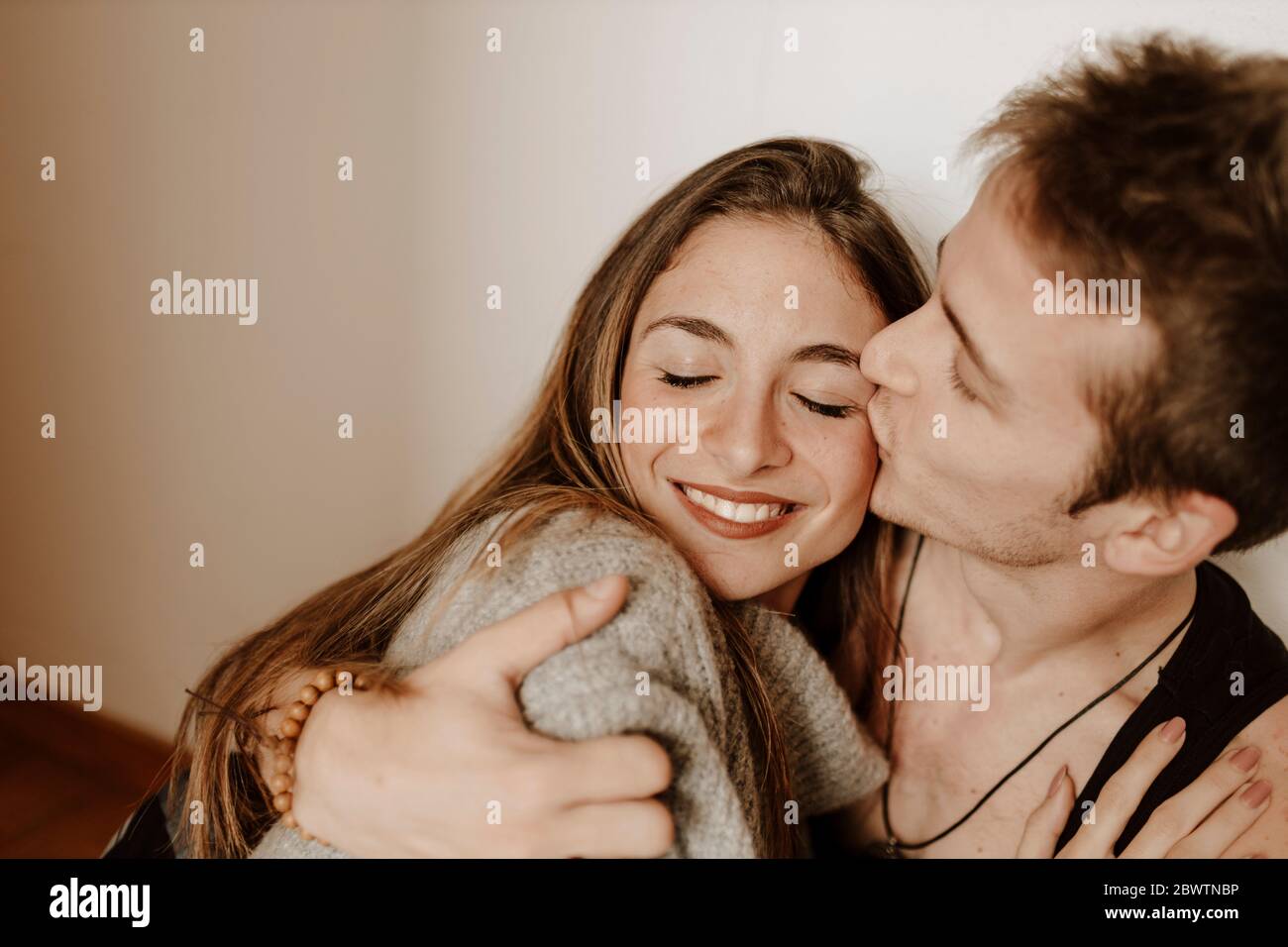 Happy young couple hugging and kissing at home Stock Photo