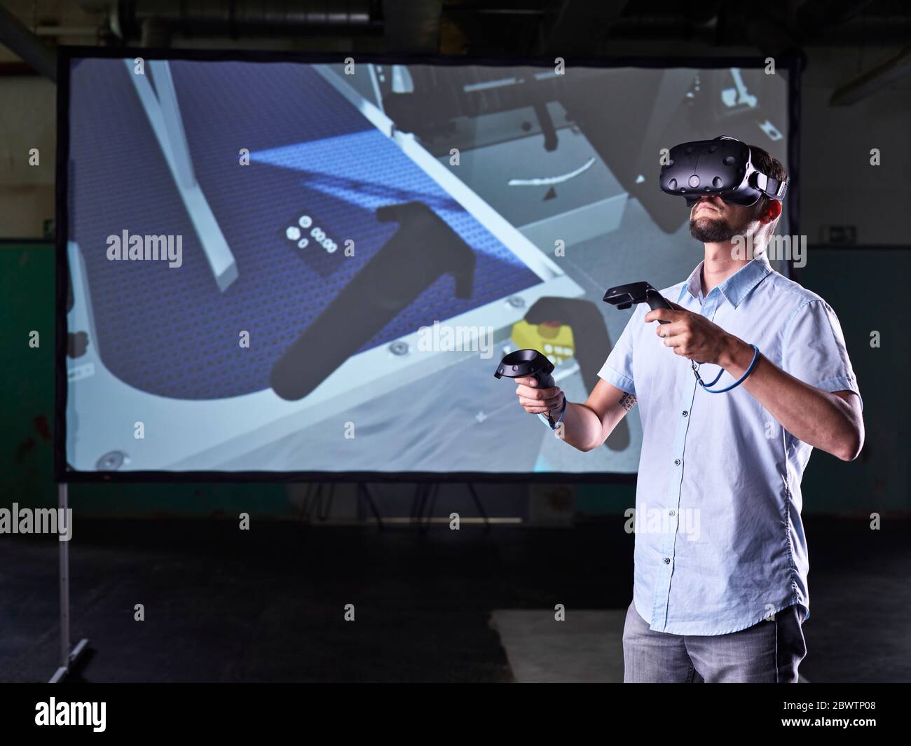 Man wearing VR glasses and using joysticks in virtual training class Stock Photo