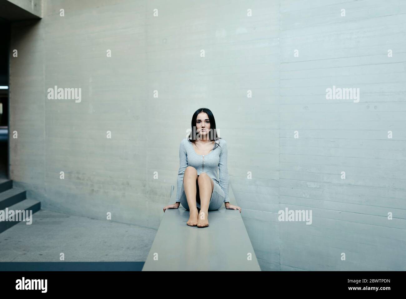 Thoughtful woman sitting on concrete wall Stock Photo - Alamy