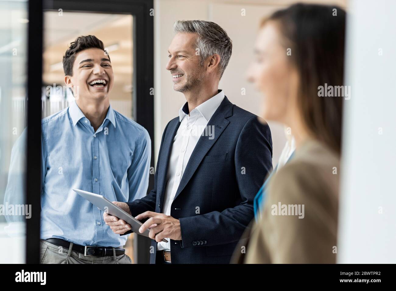 Smiling mature businessman and employees in office Stock Photo