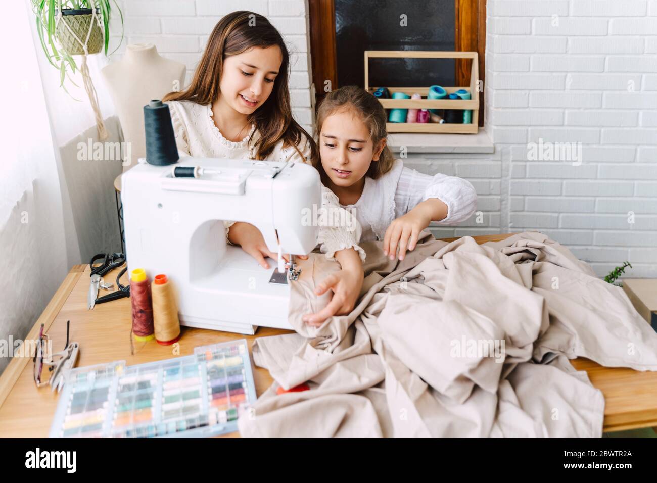 Two girls sewing at home Stock Photo