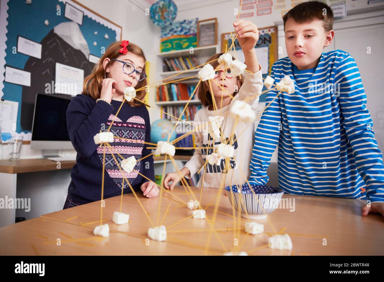 Three children setting up construction during a science lesson Stock Photo