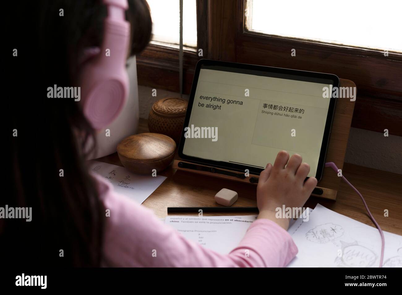 Girl translating English language in Chinese on digital tablet at desk in house Stock Photo