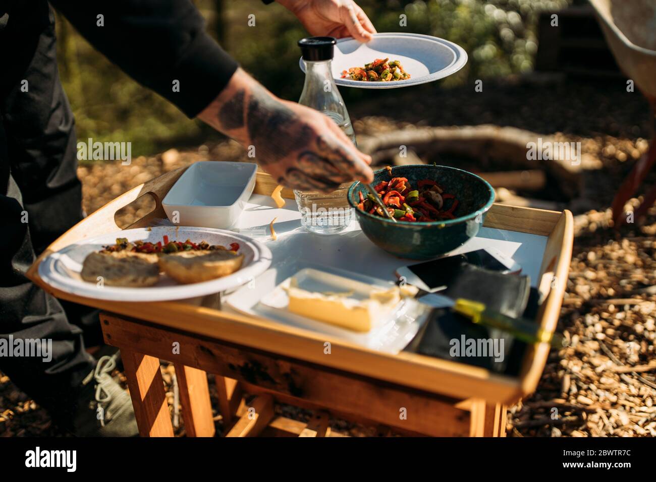 Close-up of tattooed man putting vegetarian meal on plate in garden Stock Photo