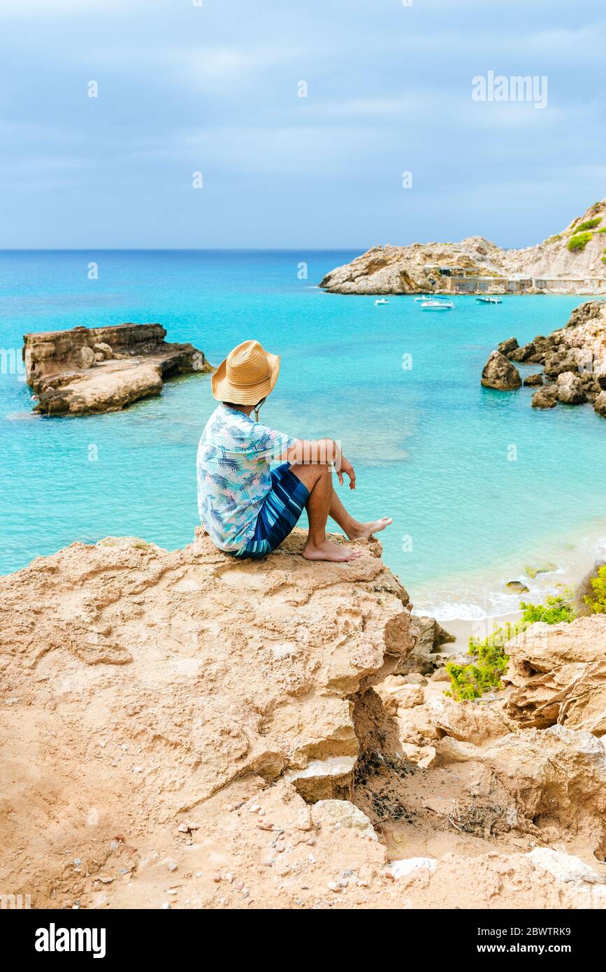 Man sitting on cliff looking at sea, Ibiza, Spain Stock Photo