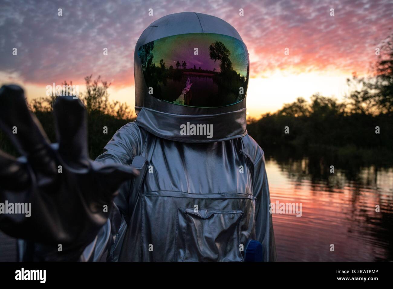 Portrait of spacewoman with raising arm at sunset Stock Photo