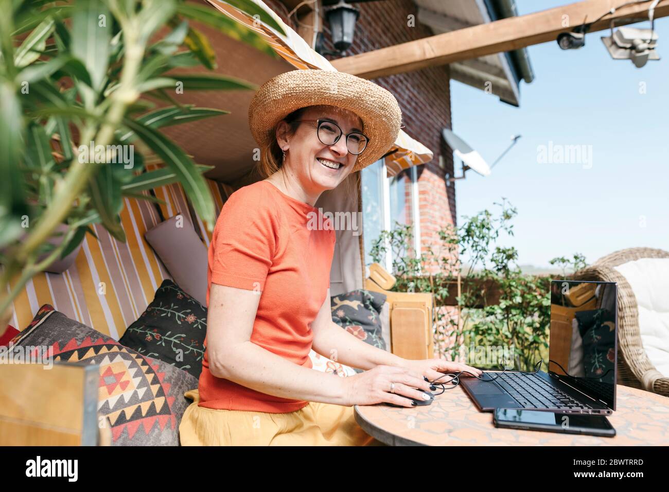 Portrait of laughing mature woman working on laptop on terrace Stock ...