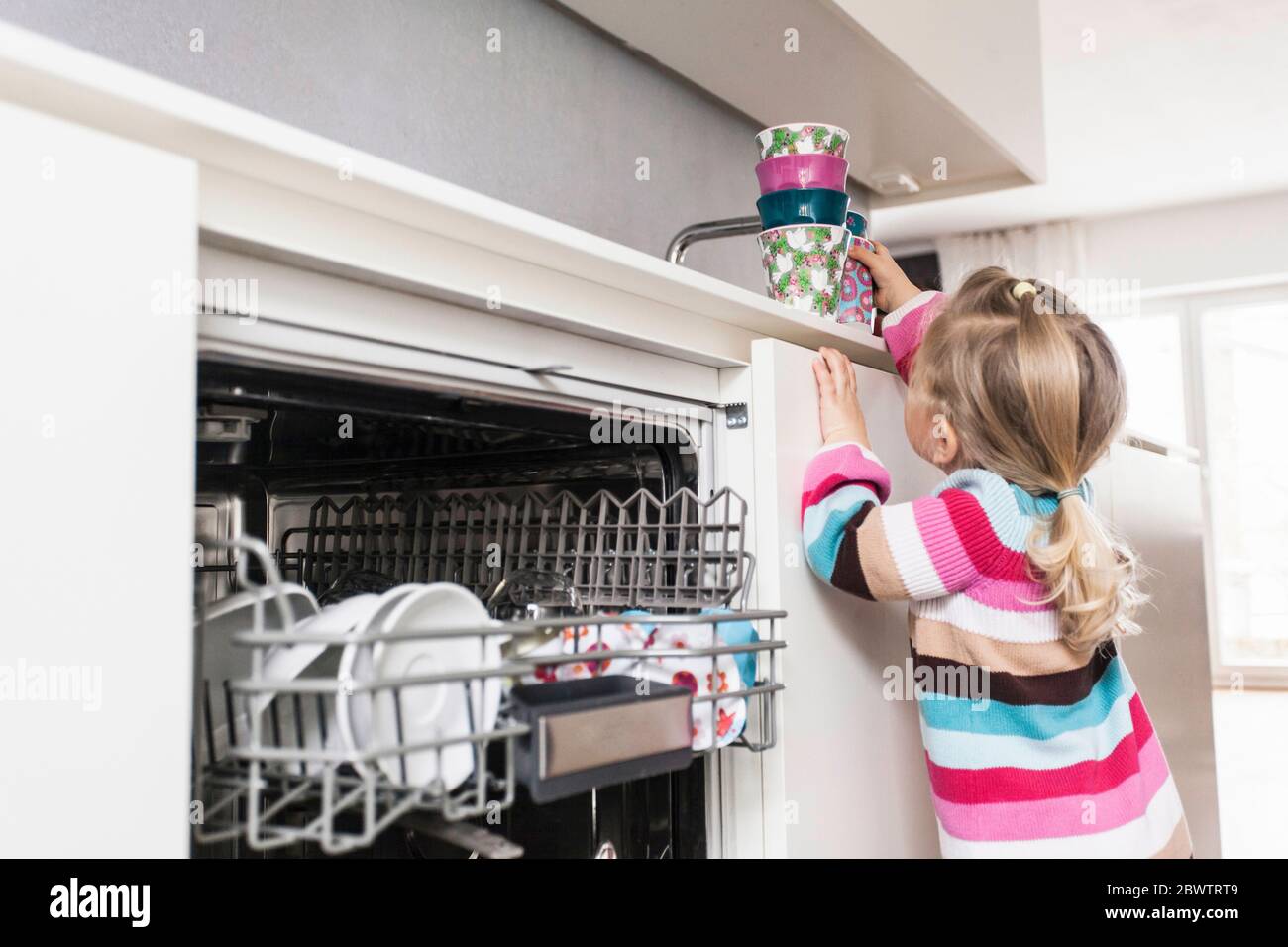 Daughter clearing the dishwasher Stock Photo
