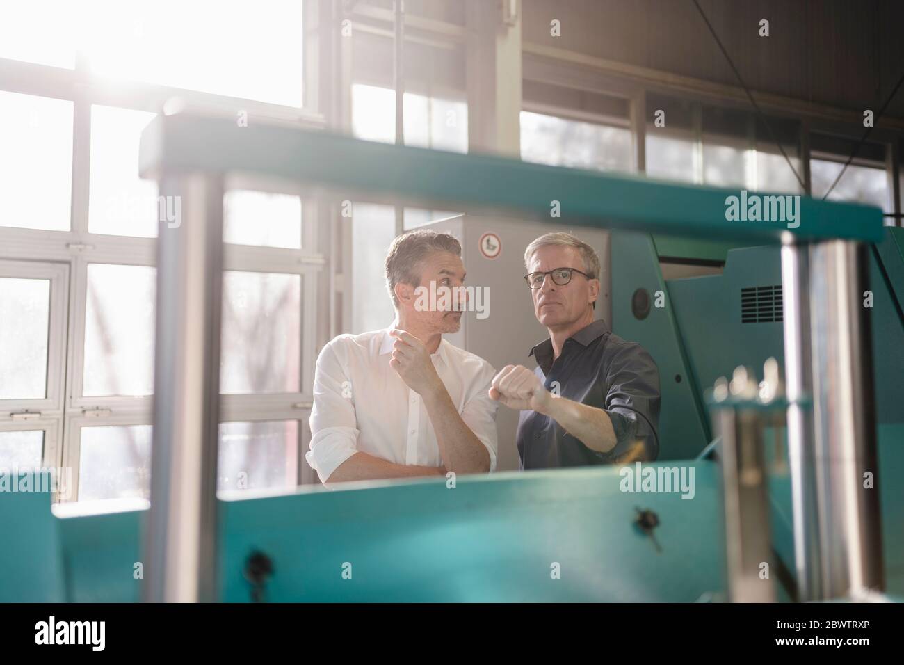 Businessmen in factory, having a meeting, discussing solutions Stock Photo