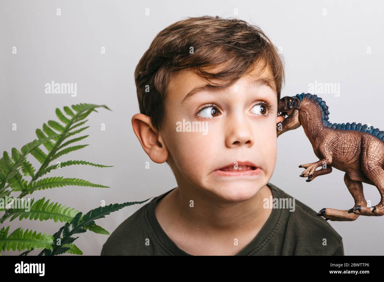 Portrait of little boy with toy dinosaur pulling funny face Stock Photo