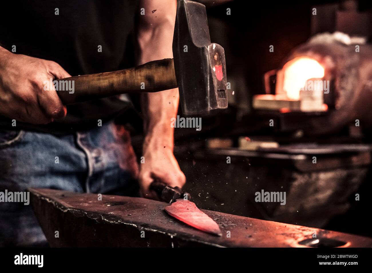 Knife maker at work, steel splinter during hammering damask steel Stock Photo
