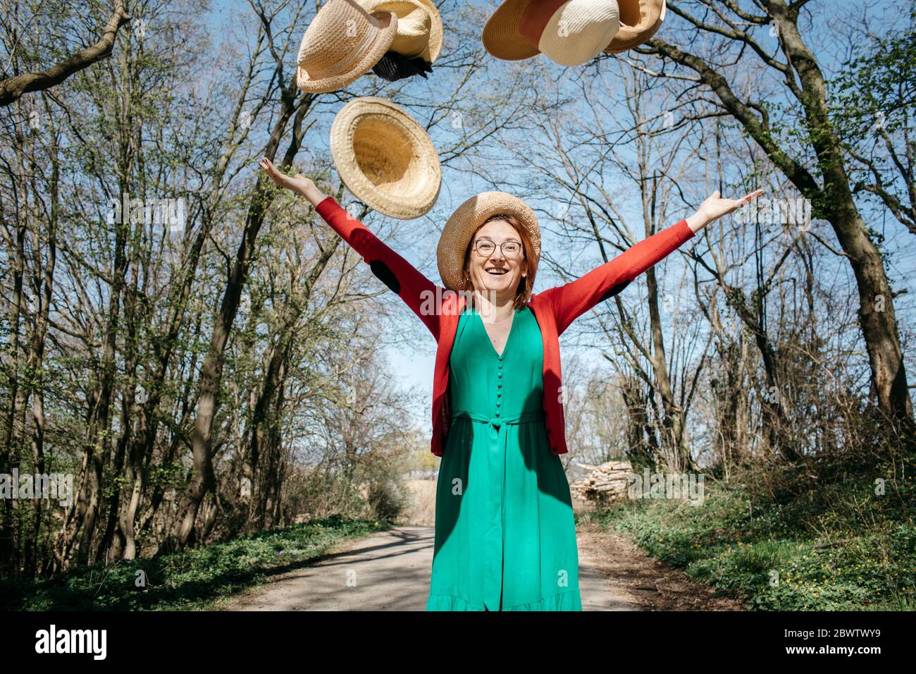 Portrait of happy mature woman throwing straw hats in the air Stock