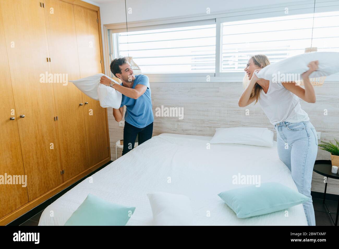 Happy carefree couple having pillow fight in bedroom at home Stock Photo
