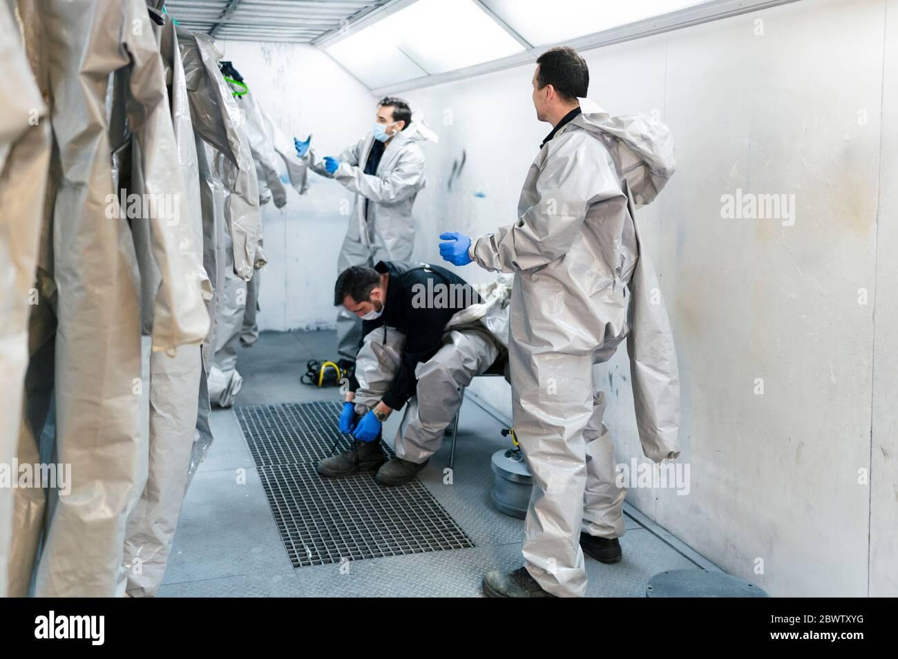 Sanitation workers getting dressed in protective coveralls inside