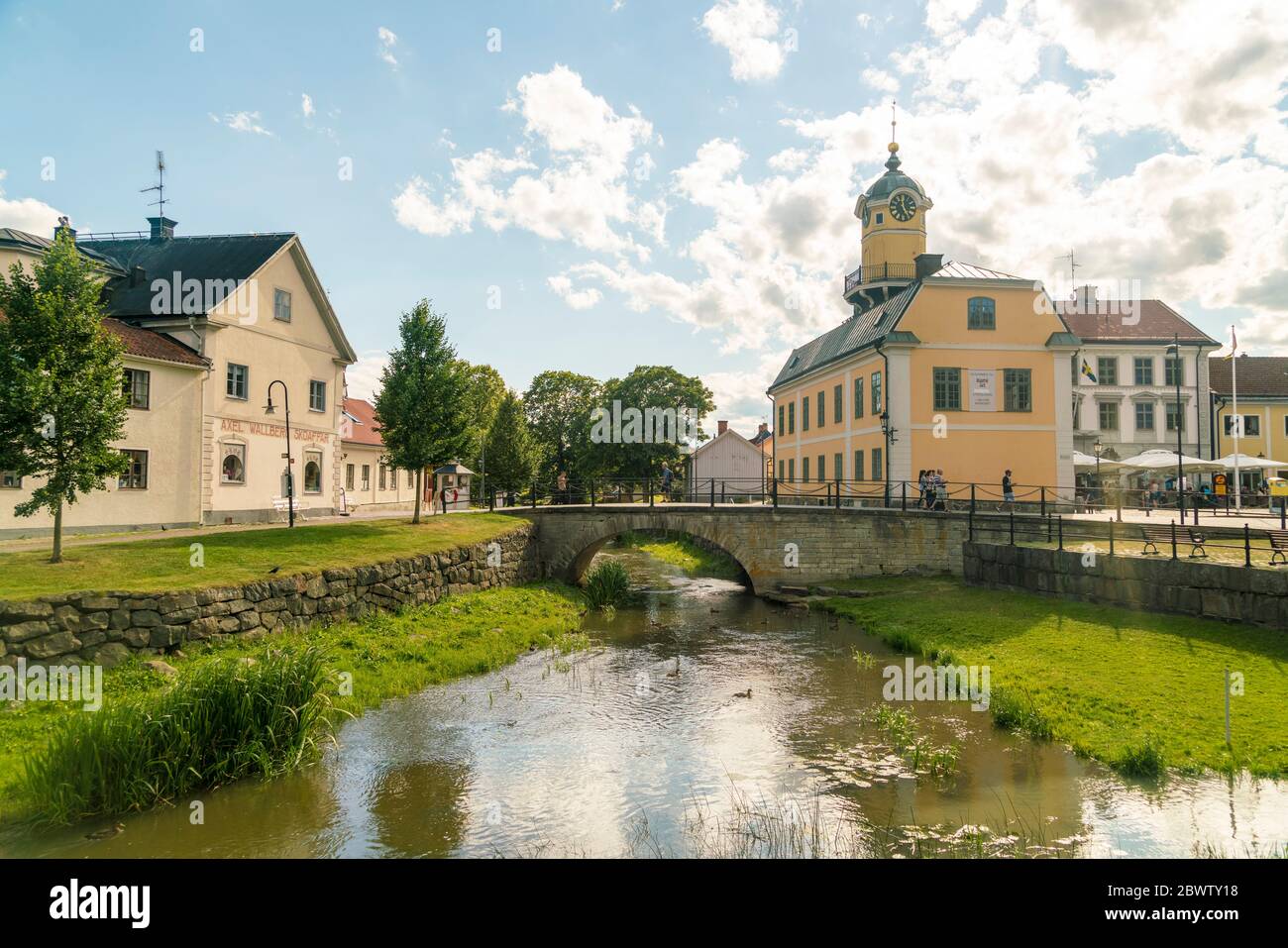 Sweden, Ostergotland, Soderkoping, Arch bridge over small city canal with town hall in background Stock Photo