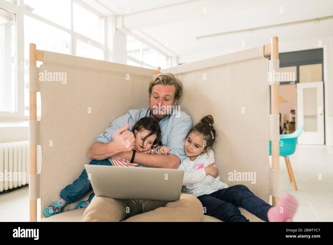 Father distracted by two daughters in home office Stock Photo