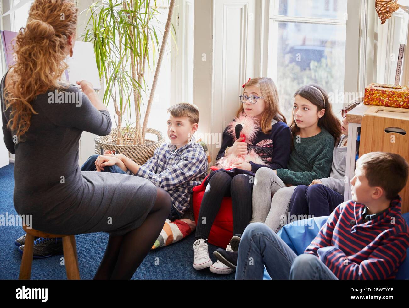 Children in a classroom during story time with the teacher Stock Photo