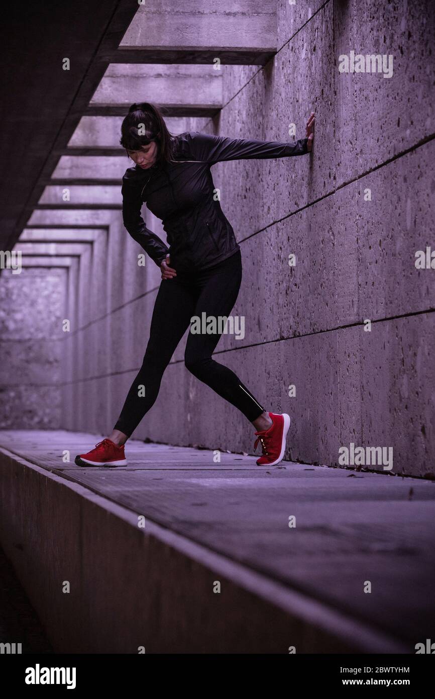 Female athlete warming up before running in pedestrian underpass Stock Photo