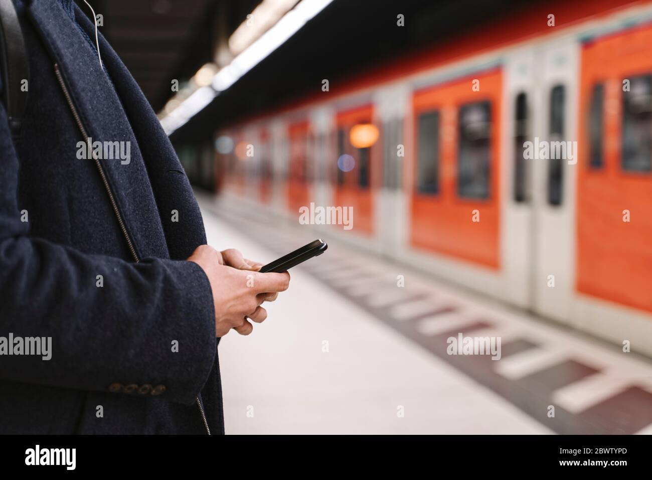 Close-up of man using smartphone in metro station Stock Photo
