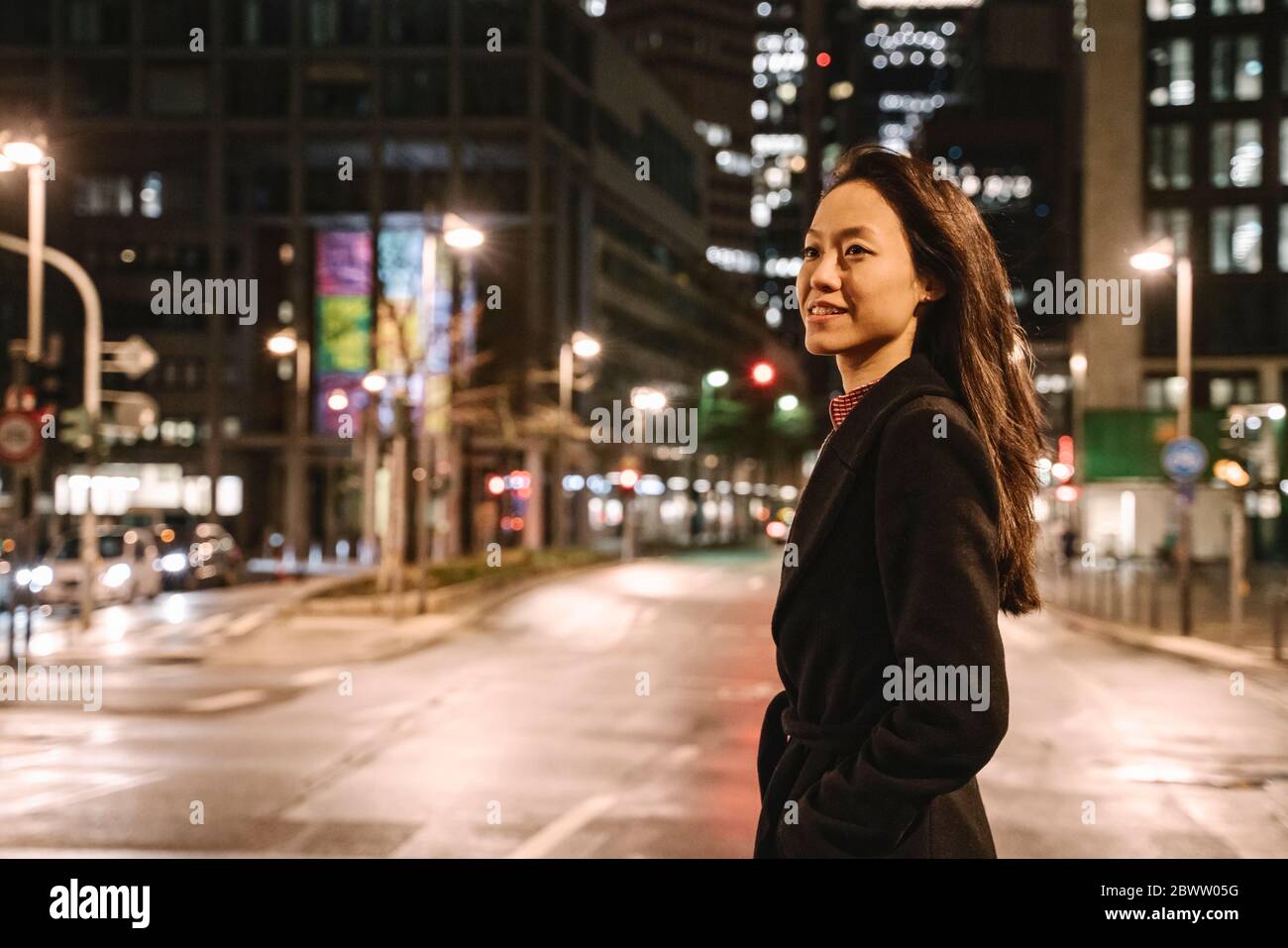 Young woman crossing the street in the city at night, Frankfurt, Germany Stock Photo