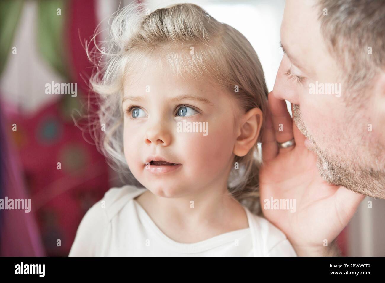 Father whispering in dauthter's ear Stock Photo