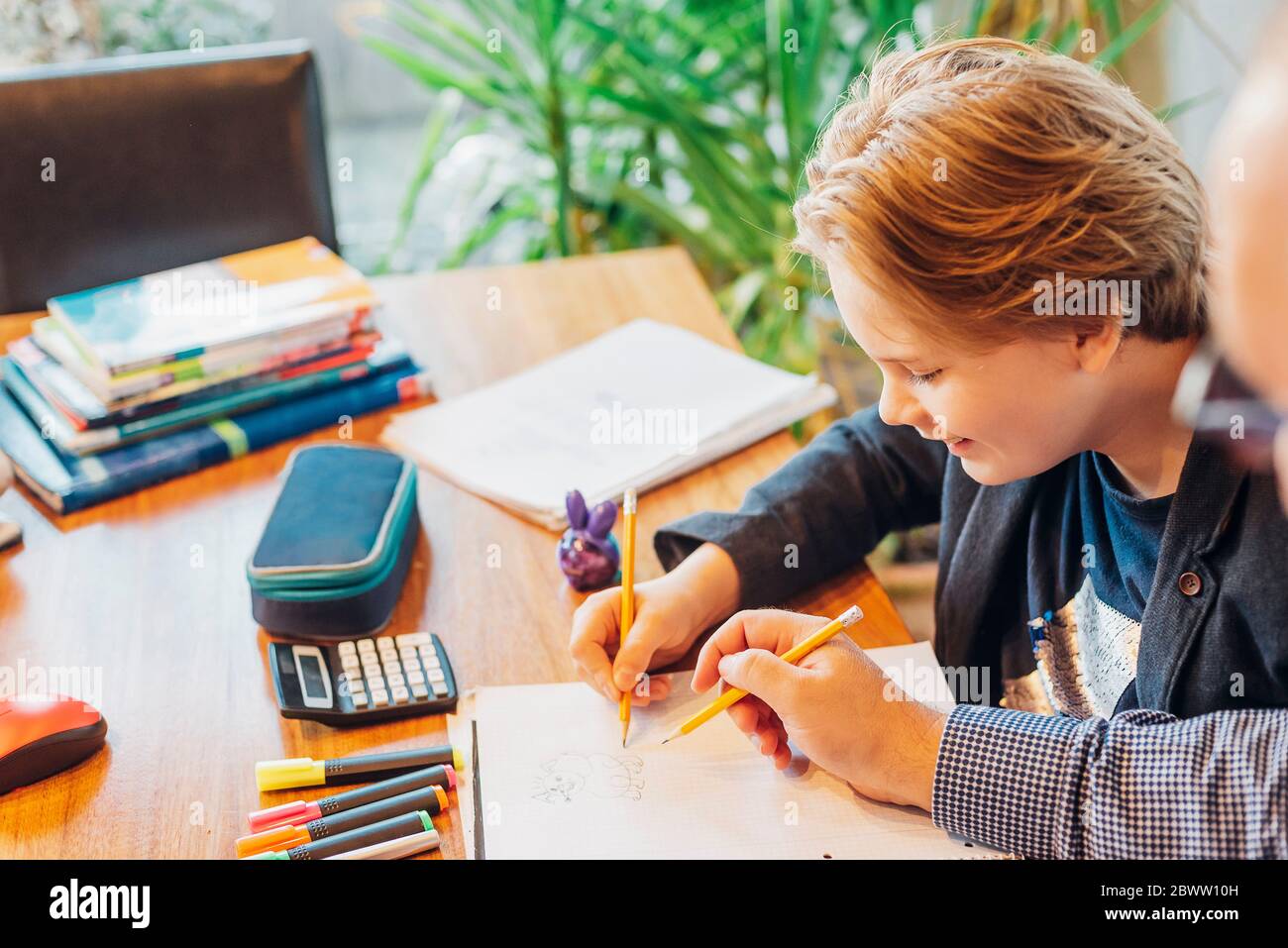 Father helping son doing homework at desk Stock Photo