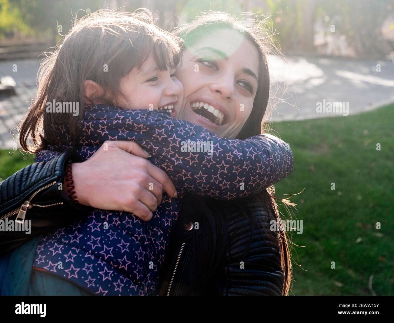 Portrait of happy little girl hugging her mother outdoors Stock Photo