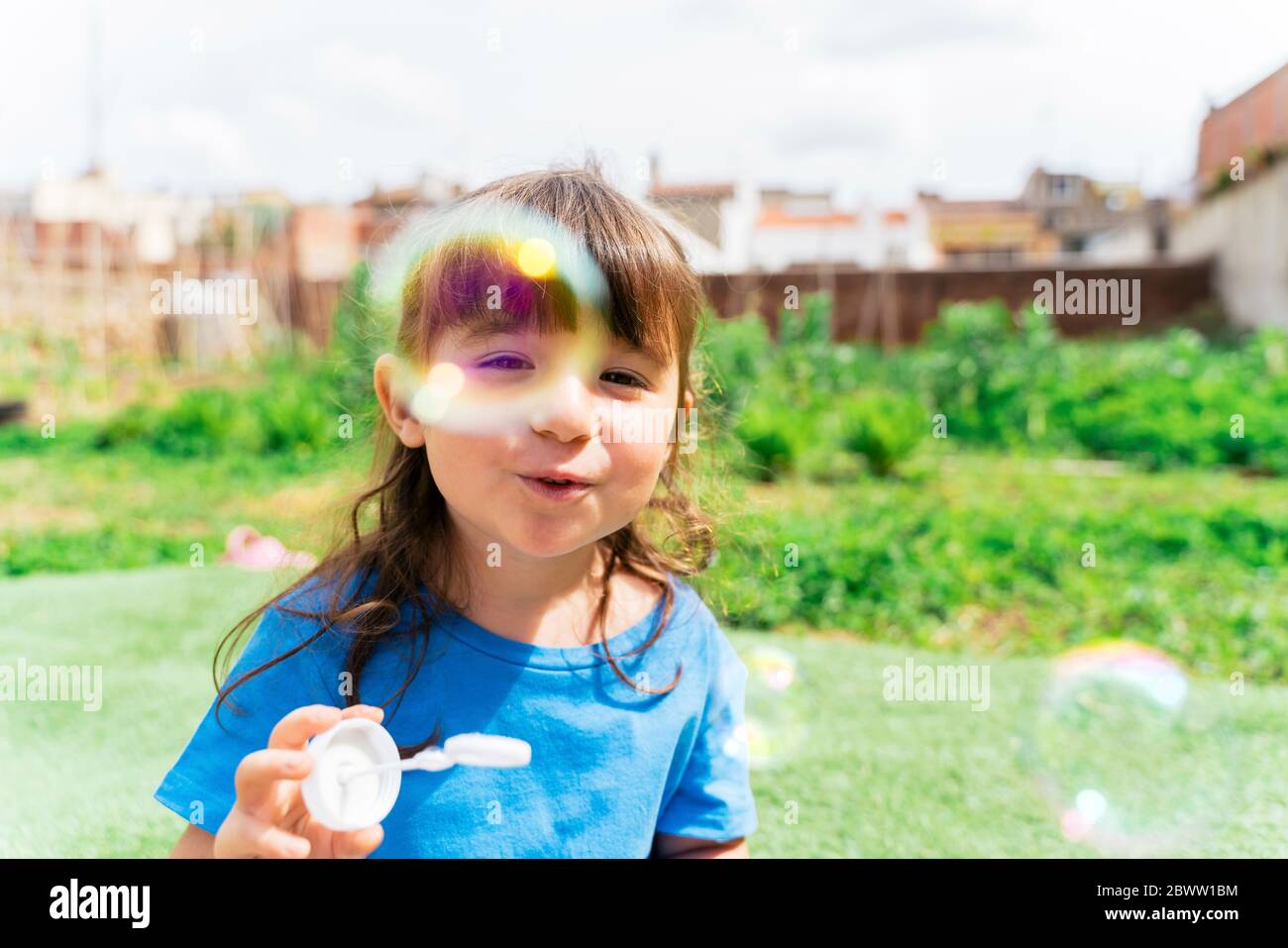 Child looking at camera blowing bubbles hires stock photography and