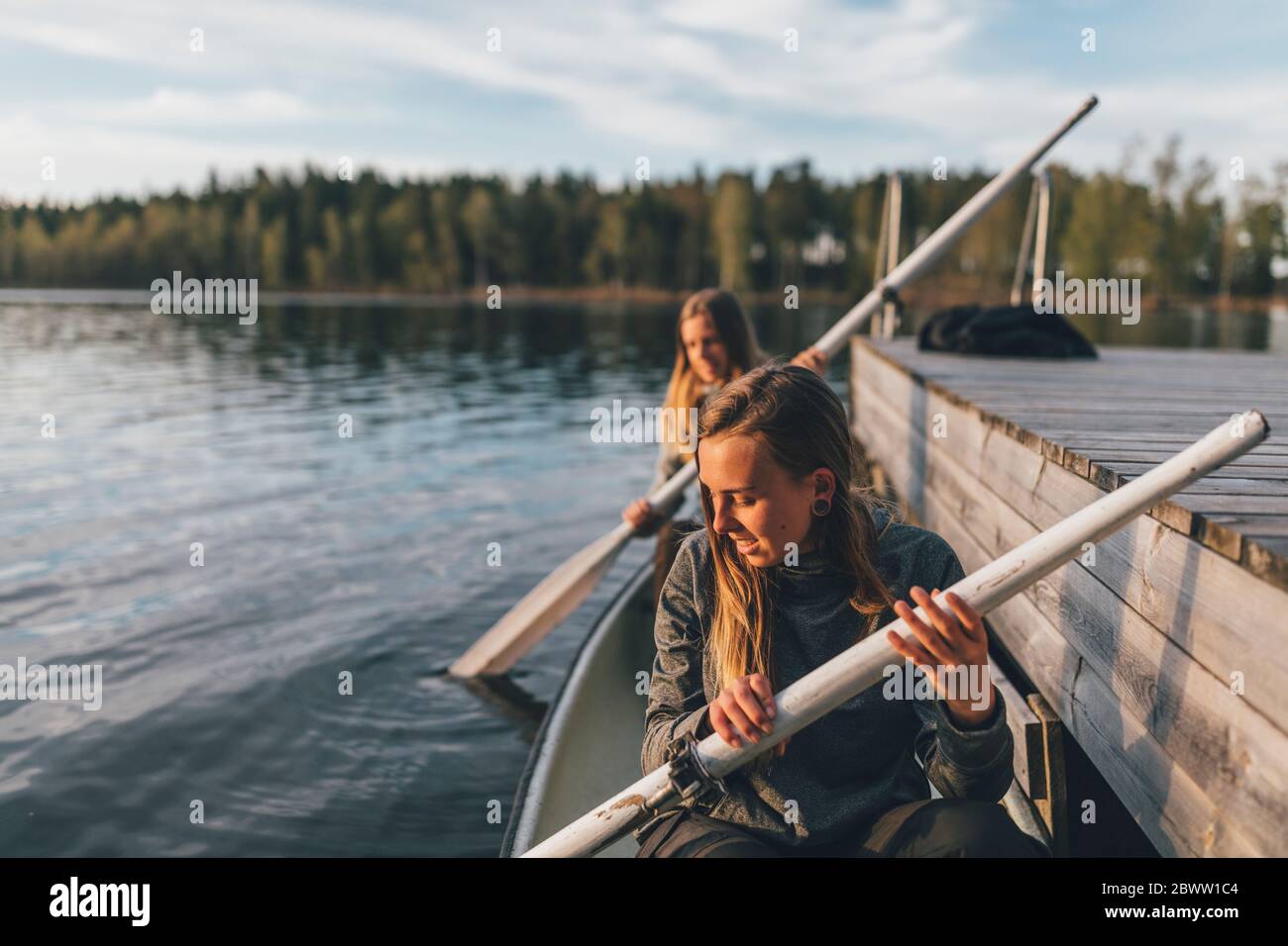 Two young women boating on lake Stock Photo