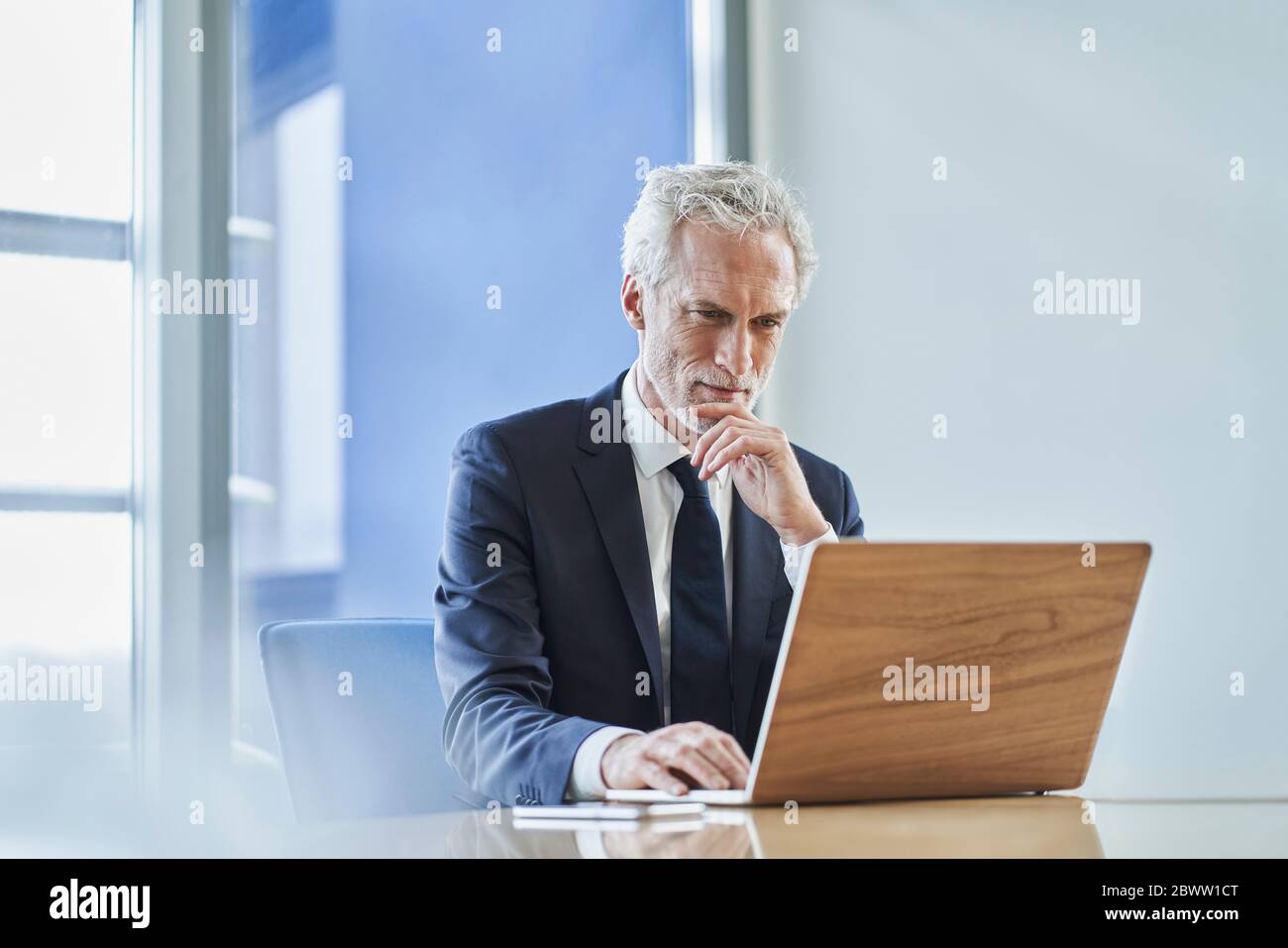 Focused businessman using laptop at desk in office Stock Photo