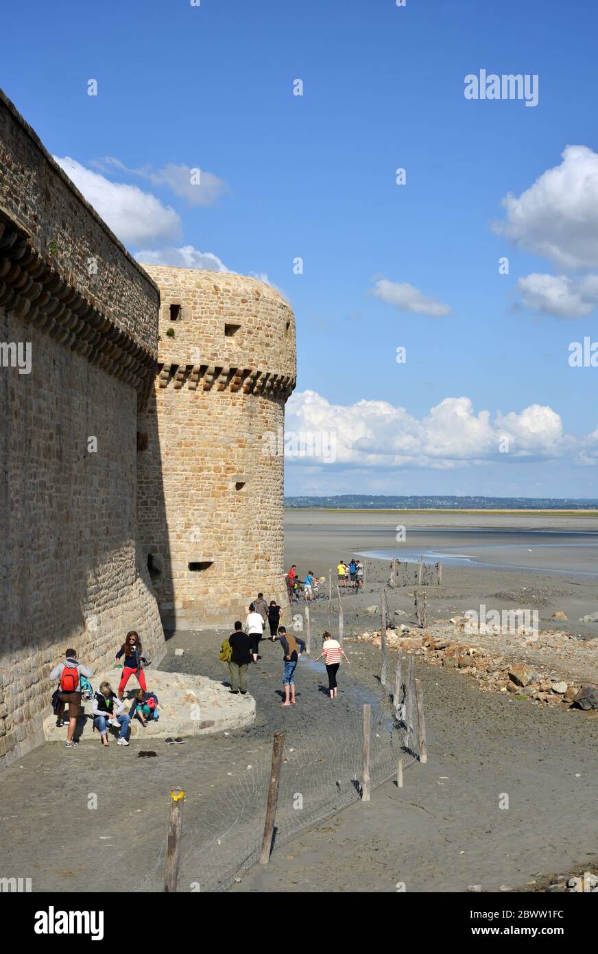 Mont Saint Michel, France, tourist preparing for a walk on low tide at the atlantic ocean near the fortress walls Stock Photo