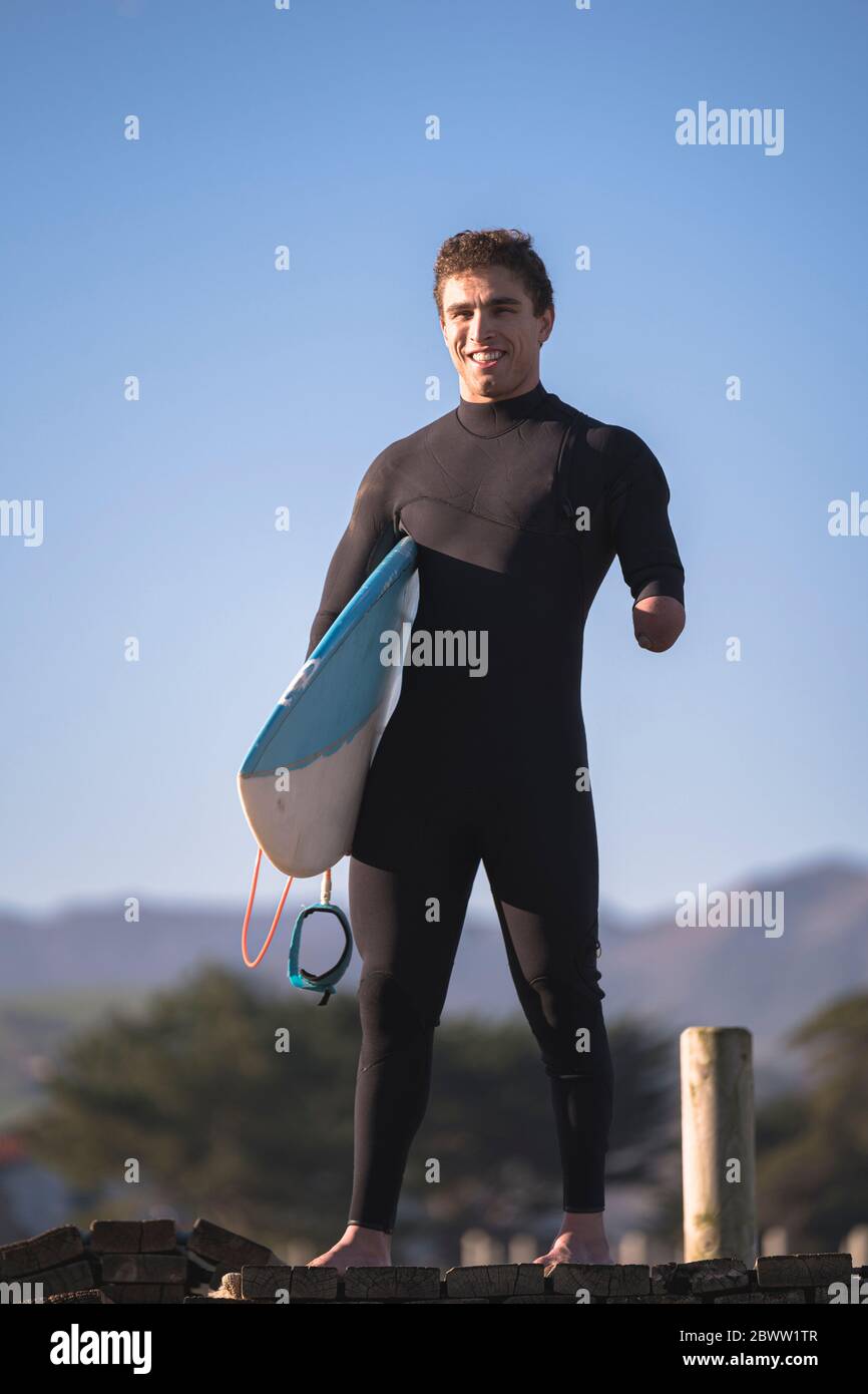 Handicapped surfer with surfboard at beach Stock Photo