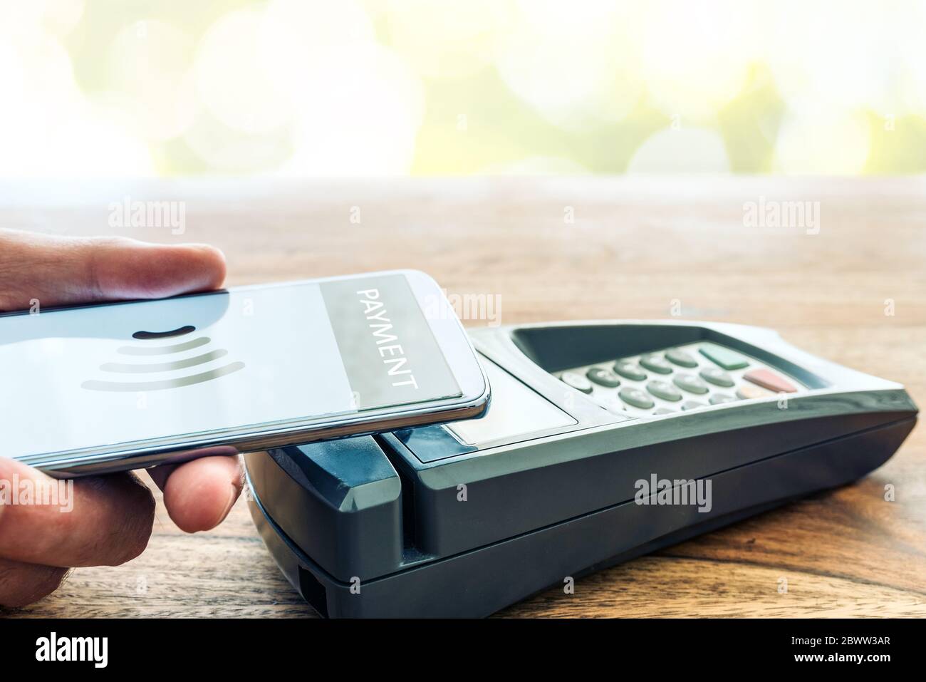contactless payment using smartphone concept, person holding phone against POS payment terminal Stock Photo