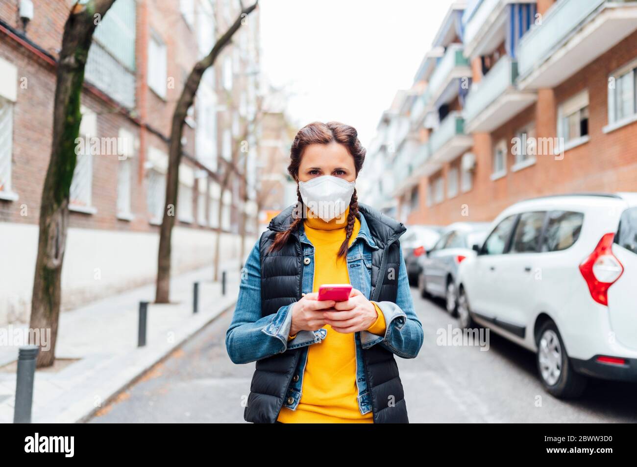 Woman wearing protective mask and using smartphone Stock Photo