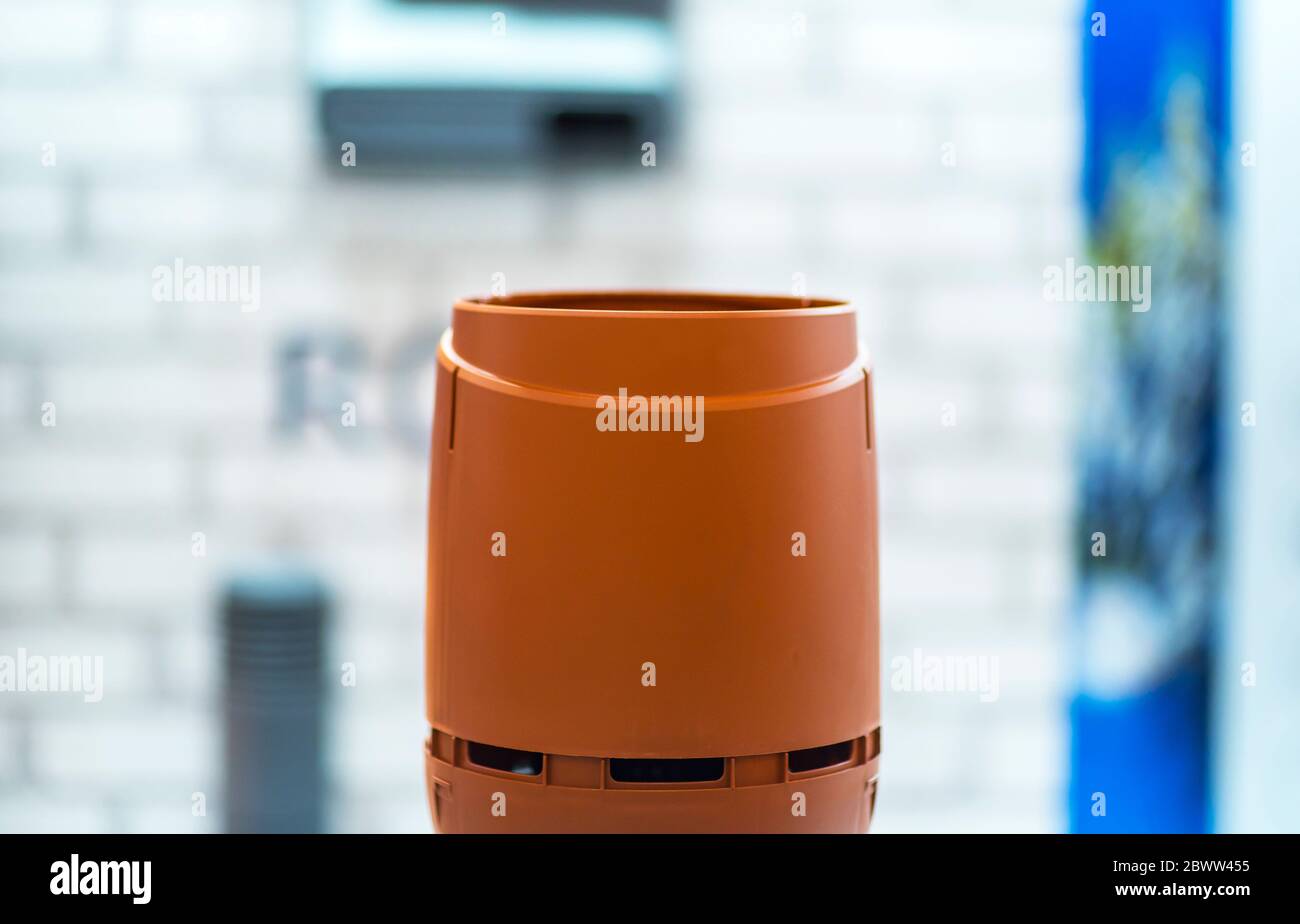 Detail of a chimney on a red classic saddle tile roof separated on a white background. Chimney with two steel pipes. Roof and chimney of family house. Stock Photo