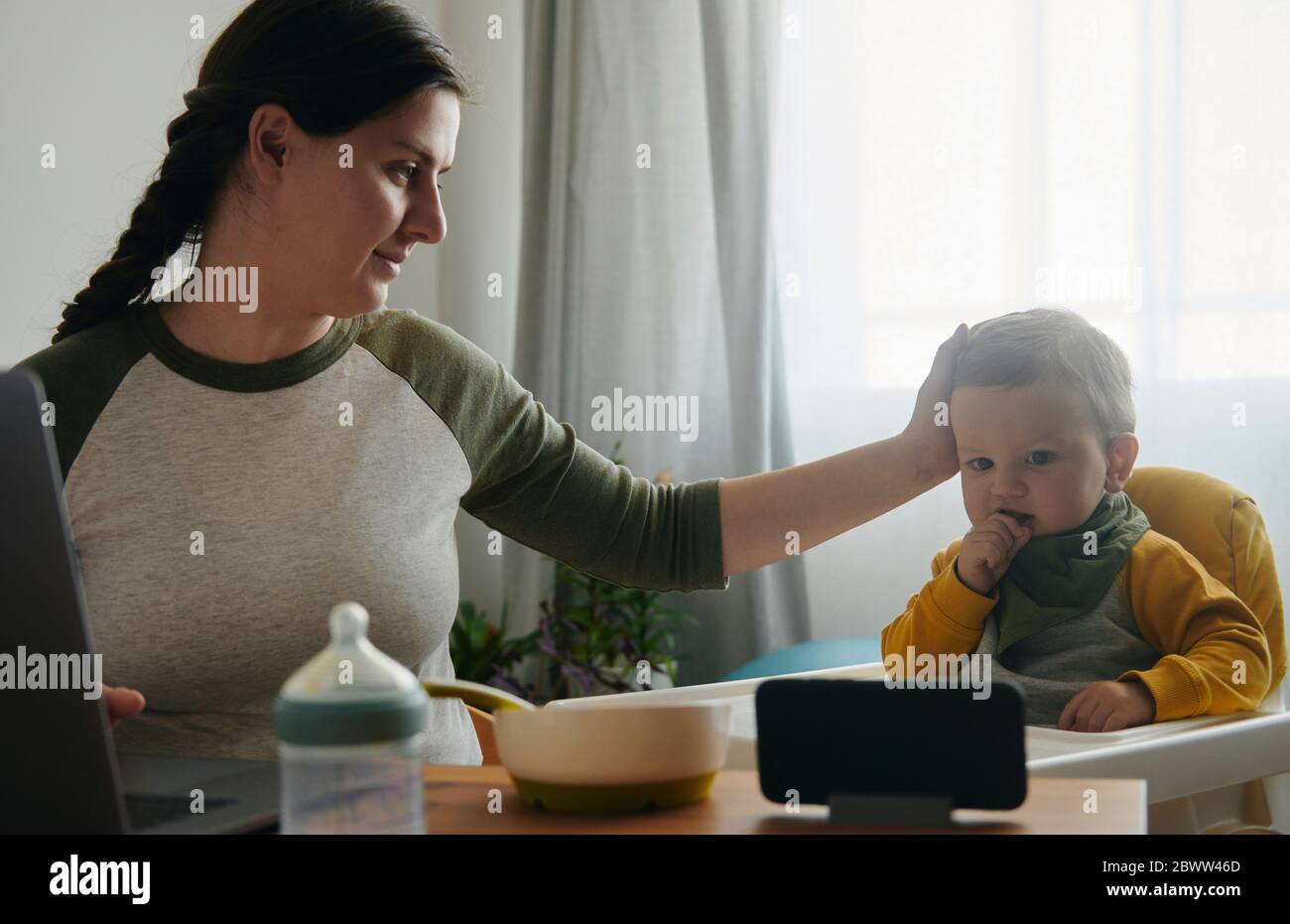Mother stroking baby boy watching movies on mobile phone Stock Photo