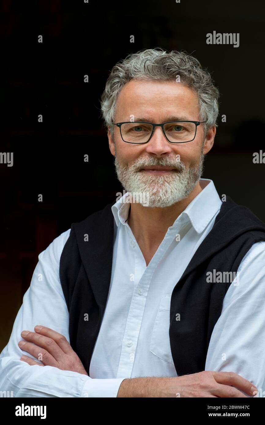 Portrait of smiling mature man against black background Stock Photo
