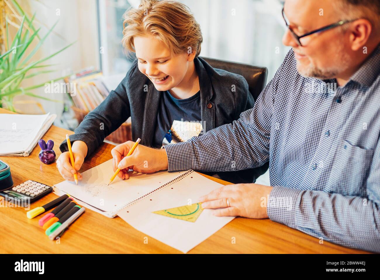 Father helping son doing homework at desk Stock Photo