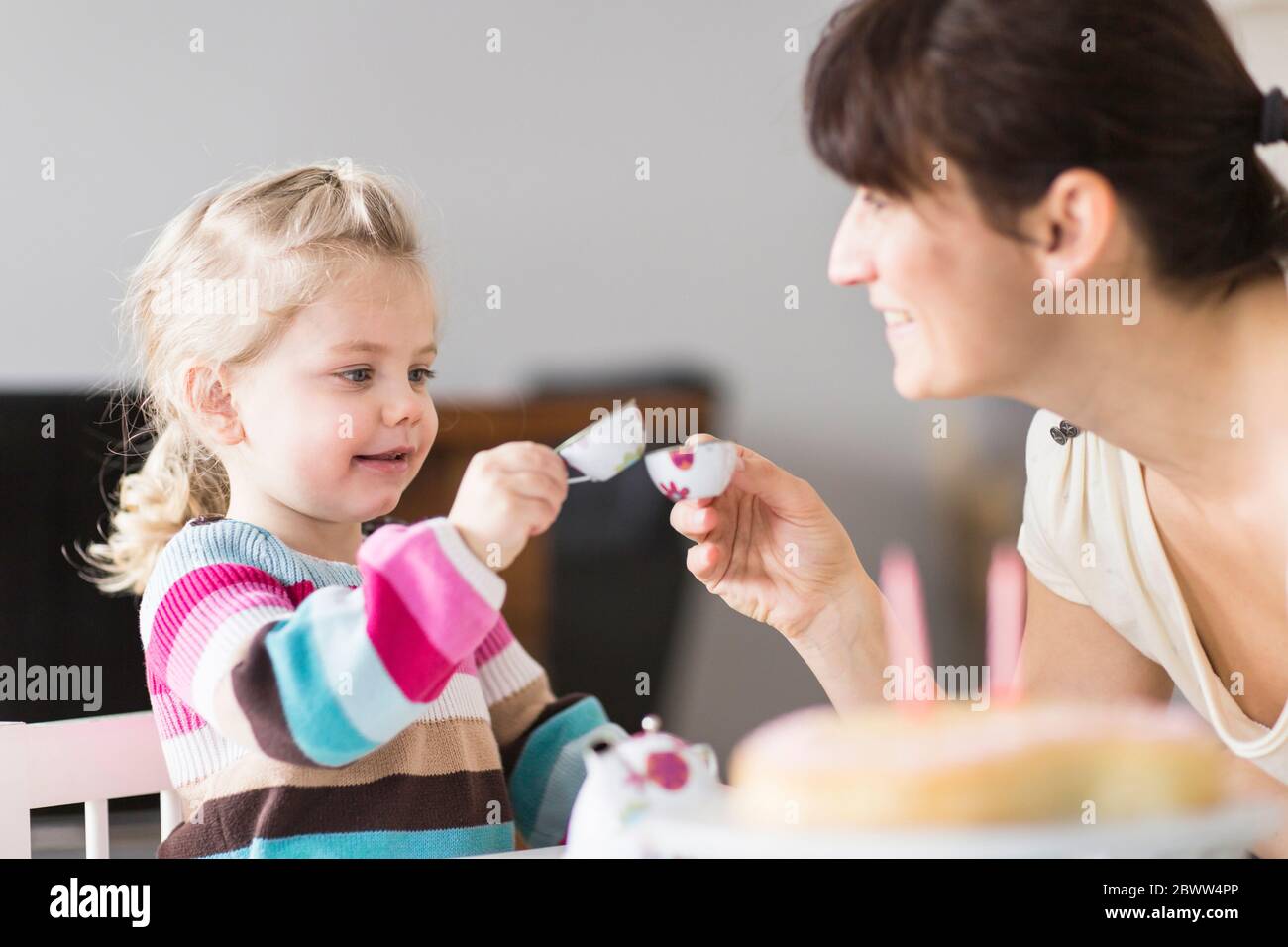 Mother and daughter playing with doll's china set Stock Photo