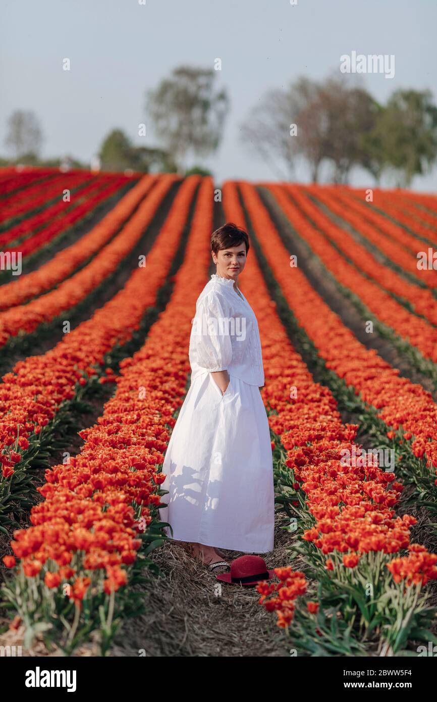 Portrait of woman dressed in white standing in red tulip field Stock Photo