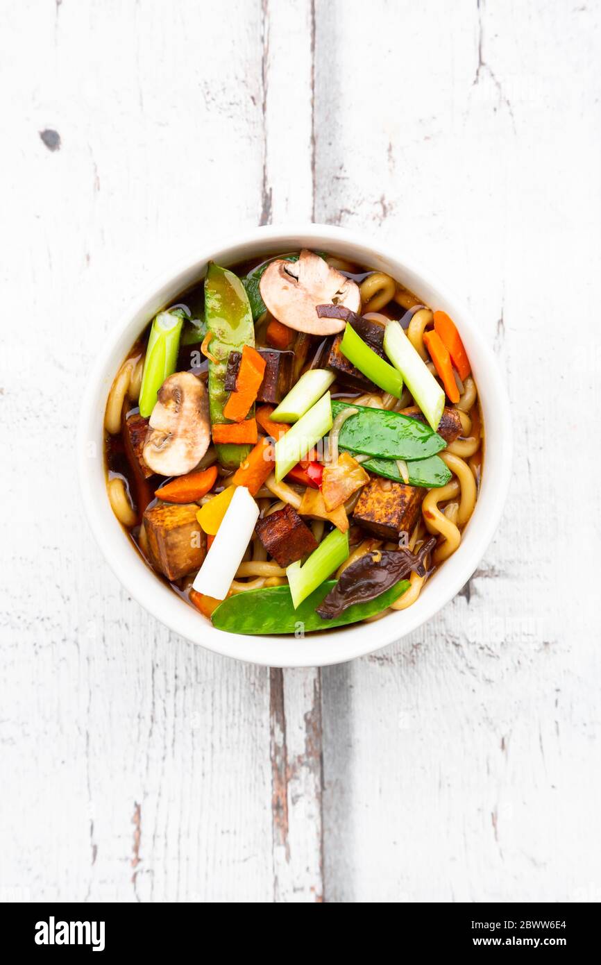 Bowl of Japanese miso soup with udon noodles, tofu, sugar snap peas