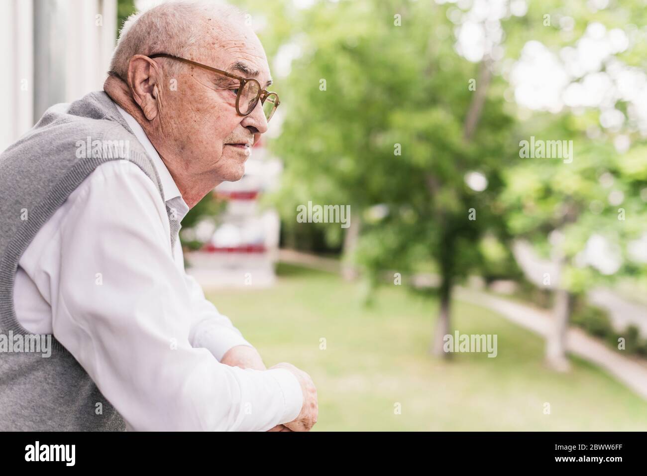 Senior man on balcony looking at distance Stock Photo